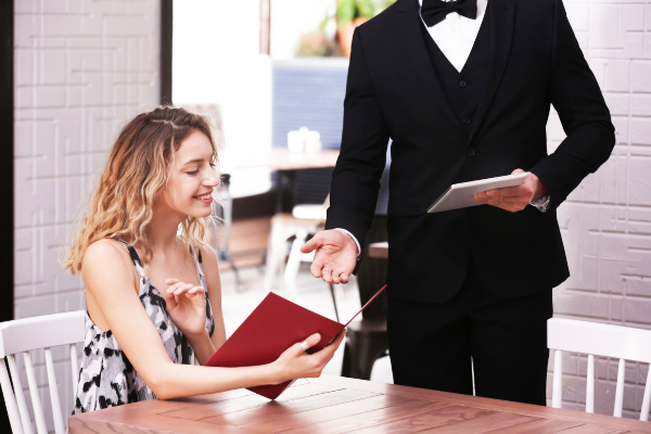 Nhân viên phục vụ tư vấn món ăn chuyên nghiệp trên menu giúp tăng trải nghiệm khách hàng tại bàn.